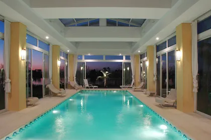 Piscina interior lujosa con techo de vidrio y vistas al exterior — proyecto L' incanto Romano , por Apaarquitectura