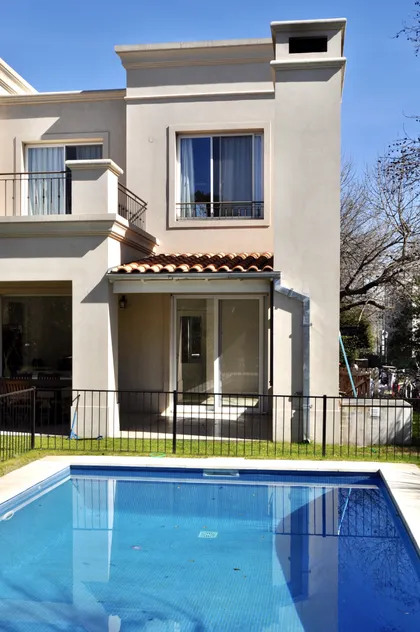 Pileta moderna con fachada de casa beige y galería exterior — proyecto Newman Benavidez, por Marconi Silva Arquitectos, en Benavidez