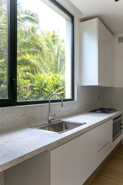 Cocina moderna con mesada de mármol y ventanal verde — proyecto Bosque Chico, por Estudio Arq. María Sioli, en Garin