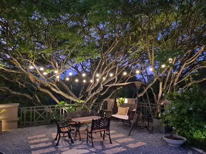 Patio nocturno con árboles iluminados y muebles de diseño — proyecto Los pasos de Justina. Club de Campo El TIPAL, por Marina Caballer