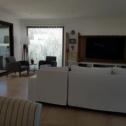Living moderno con sofá blanco y ventanales amplios — proyecto Casa FA, por Vicky Hurrell, en Mar del Plata