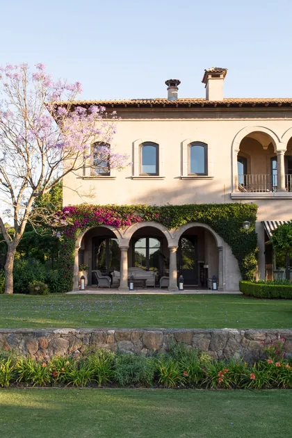Villa mediterranea con galerías, jardín floral y cesped verde — proyecto Casa Toscana , por Estudio Du 