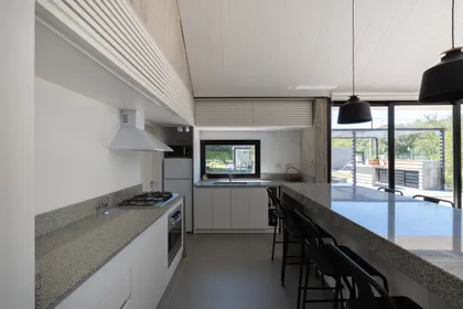 Cocina minimalista con isla central y mesada de mármol gris — proyecto Casa TT, por Grupo Studio, en Villa Allende