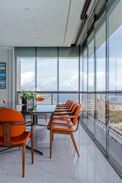 Terraza con comedor moderno, sillas naranjas y vista panorámica de ciudad — proyecto Apto S | A, por Arquitetura Paulo Melo E Paulo