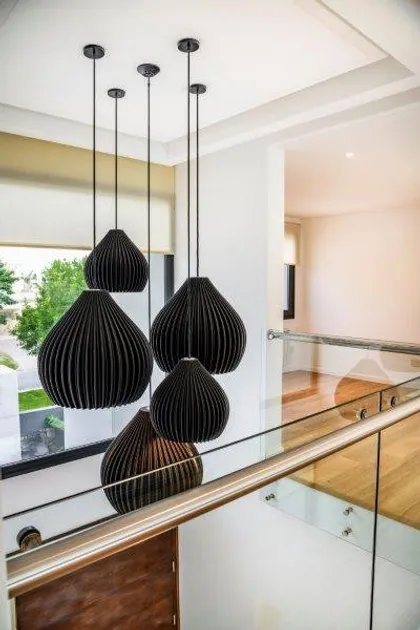 Luminarias colgantes negras escalonadas en escalera moderna con baranda de vidrio — proyecto trv 427, por Estudio Arq Daniel Tarrio
