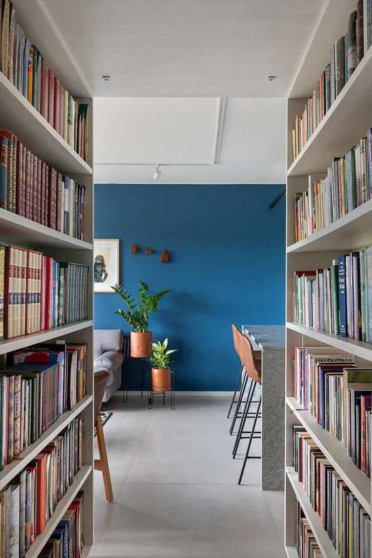 biblioteca moderna con pared azul, estantes blancos y escritorio minimalista — proyecto Apartamento 415N, por Coda Arquitetos