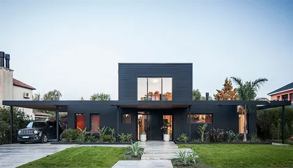 Casa moderna negra con techo voladizo y puertas naranjas — proyecto Casa coco, por Estudio PK, en B1648 Tigre