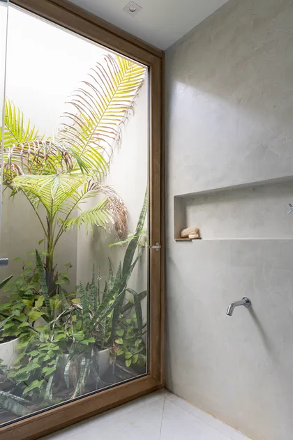 Baño minimalista con jardín interior y pared de microcemento — proyecto Casa Al Agua - Grupo PAUTA, por Gaby Alfonso, en Belén de Escobar