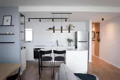 Cocina y living moderno, minimalista, con isla blanca y detalles negros — proyecto Departamento Airbnb, por Jeitinho Estudió Creativo, en La Plata