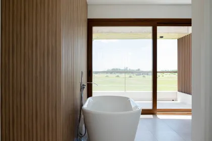 Baño moderno con bañera exenta y vista al campo — proyecto CASA GOLF, por SEDE Arq., en Av. Pereda S/N