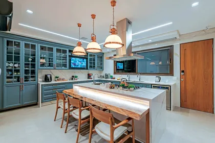 Cocina moderna con isla central, muebles azules y lámparas cobre colgantes — proyecto Projeto Destaque Club&Casa, por Andrea Carvalho Arquitetura