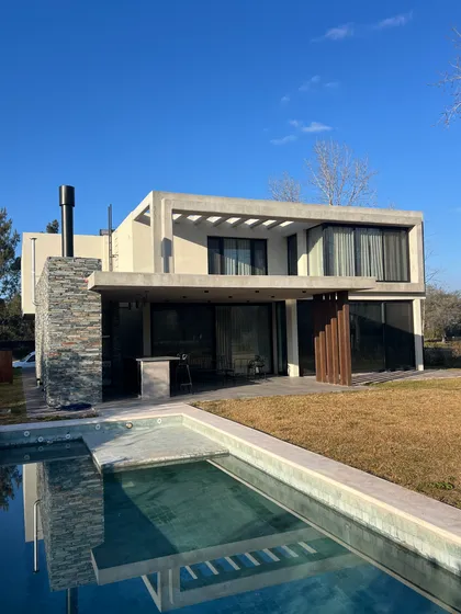 Casa moderna con pileta espejo y fachada de hormigón blanco — proyecto CASA LR 138 - SOFITEL LOS CARDALES, por Carolina Depetris, en B2814 Los Cardales