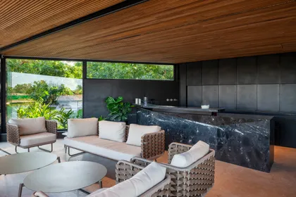 Living comedor semi-cubierto moderno con isla de cocina de mármol y detalles en madera — proyecto Casa Porsche, por Remy Arquitectos, en Buenos Aires