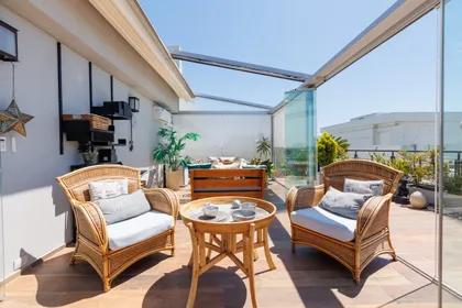 Terraza moderna con sillones de ratán y vista urbana — proyecto TOLDER - PERGOLAS, por Argentina en Obra 2024, en Rincón de Milberg