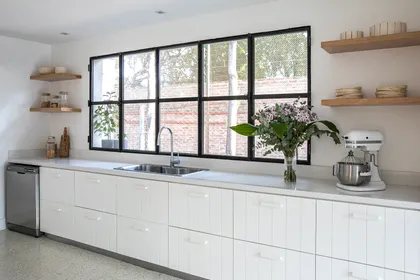 Cocina moderna con ventana industrial y muebles blancos — proyecto Laguna del Sol, por Parq Estudio, en Tigre