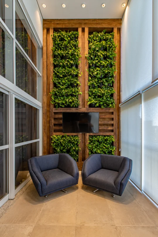 Balcón moderno con sillones grises y muro verde vertical — proyecto Duo Morumbi, por Pricila Dalzochio