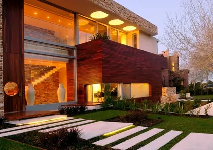 Fachada moderna de casa con madera oscura y grandes ventanales — proyecto Casa Cinta, por Barrionuevo Arquitects, en B2814 Los Cardales