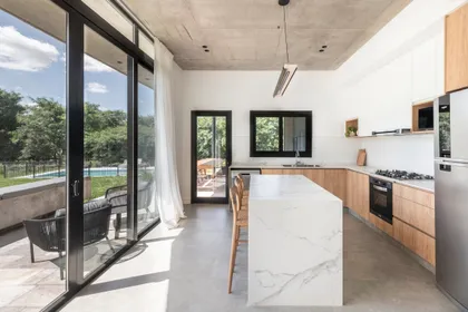 Cocina moderna abierta con isla grande y ventanales amplios — proyecto Casa San Matías, por BK Arquitectos, en Belén de Escobar