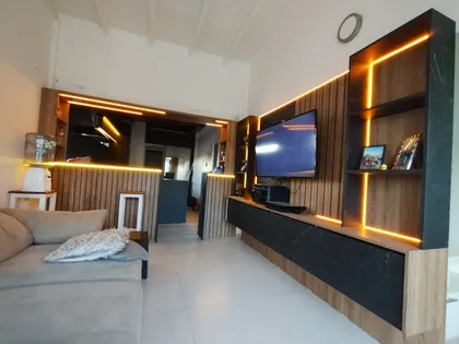 Living moderno con paredes de madera, iluminación cálida y sofá seccional — proyecto Diseño personalizado a gusto del cliente , por Saavedra Amoblamientos , en Pinamar