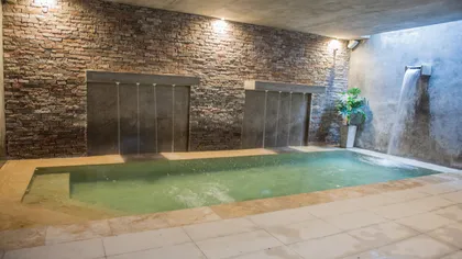 Piscina interior con paredes de ladrillo expuesto y cascada — proyecto Villa Isidro Hotel Boutique & Spa, por Hermann Arquitectos, en San Isidro