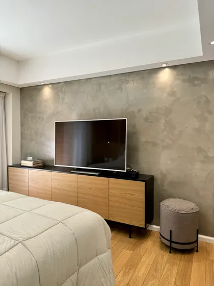 Dormitorio moderno con pared de microcemento texturado y mueble bajo de madera — proyecto Olleros, por MDBK Arquitectura, en Belgrano