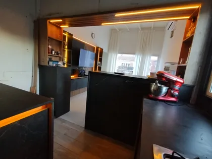 Cocina moderna con isla de mármol negro y detalles en madera — proyecto Diseño personalizado a gusto del cliente , por Saavedra Amoblamientos , en Pinamar