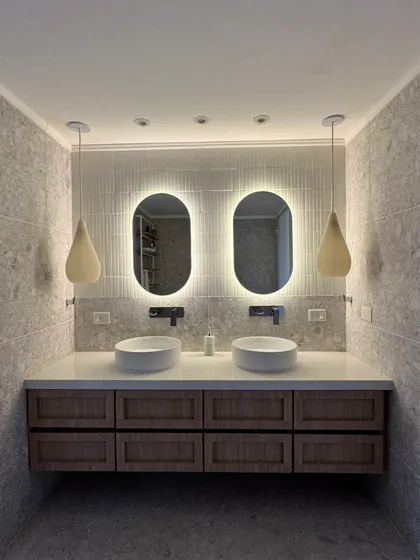 Baño moderno con doble vanitory, espejos ovalados retroiluminados y luces colgantes — proyecto Lafinur, por MDBK Arquitectura, en Palermo