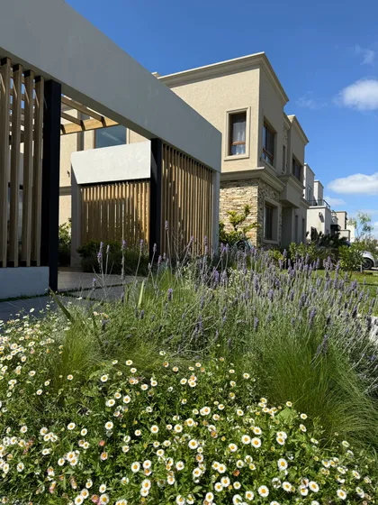 Fachada moderna con jardines de lavanda y margaritas — proyecto CARPINCHOS, por Baires Green, en Nordelta