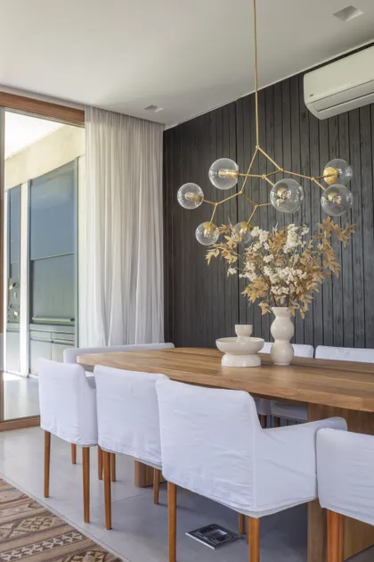Comedor moderno con mesa de madera y lámpara colgante dorada — proyecto CASA OrAz, por Alfredo Orfila arquitectura, en San Isidro