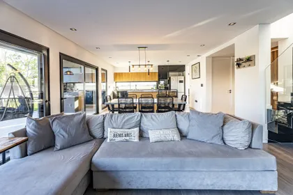 Living comedor moderno, luminoso, con sofá amplio y detalles en madera — proyecto Casa ALM57, por EZ architects, en Canning