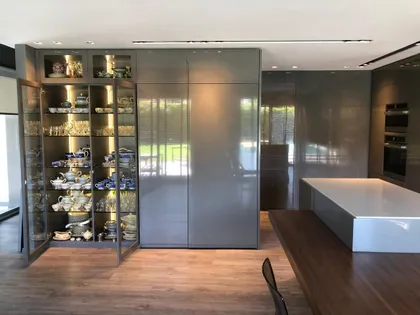 Cocina moderna abierta con isla central y gabinetes altos de vidrio — proyecto Casa Nordelta, por Etude Interiorismo, en Nordelta