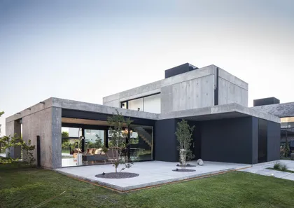 Casa moderna de hormigón y paneles negros con patio y grandes ventanales — proyecto CASA EH, por GMARQ