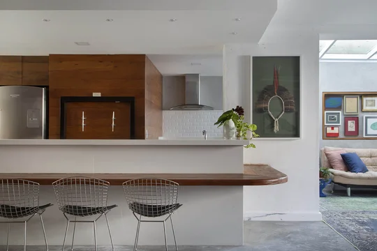 Cocina moderna con isla de madera y taburetes metálicos diseño — proyecto Casa Jardim Guanabara, por Amanda Miranda