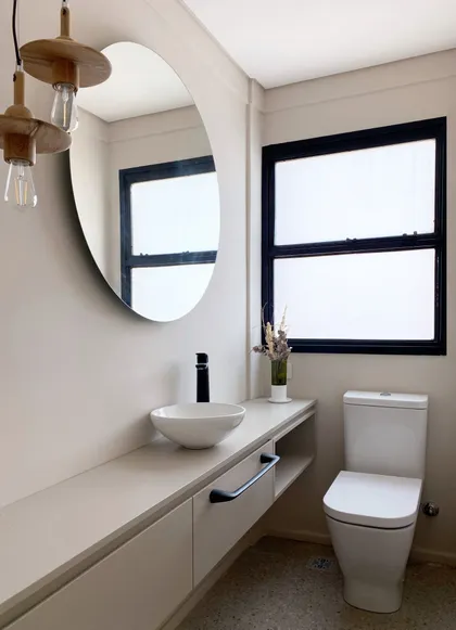 Baño minimalista con espejo redondo, mesada blanca y ventanal con marco negro — proyecto Obra MGLTS , por Ideï Arquitectura