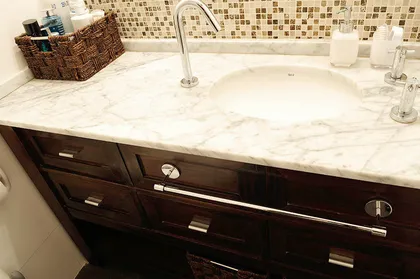 Baño con mesada de mármol blanco, vanitory oscuro y azulejos — proyecto Marcelo T de Alvear, por Rioja Arquitectura, en Recoleta