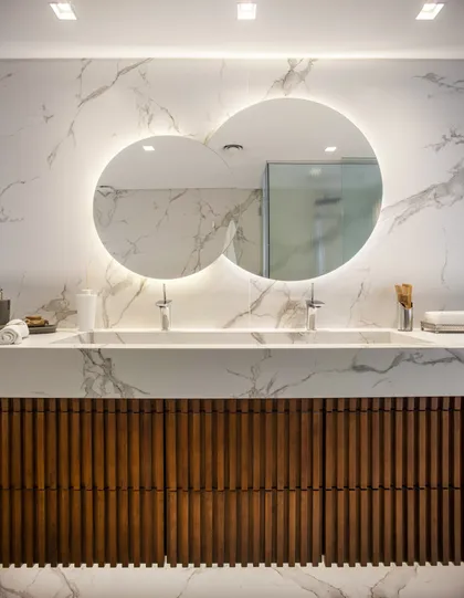 Baño moderno con doble vanitory y espejos ovalados retroiluminados — proyecto Pacífico BRT, por Vanguarda Arquitectos, en CABA