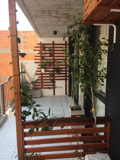 Terraza de balcón con jardines verticales y estructura de madera — proyecto Proyecto Cucha Cucha - CABA, por Ivan Lerner, en CABA