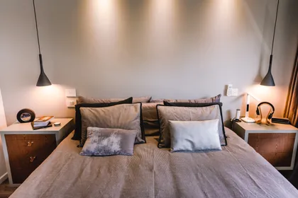 Dormitorio contemporáneo con cama doble, lámparas colgantes y mesitas de madera — proyecto Cabrera, por Tali Estudio, en Palermo