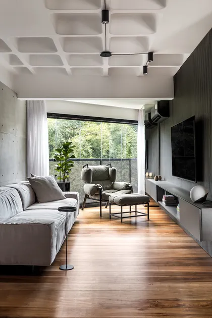 Amplio living moderno con ventanal al bosque y techo artesonado — proyecto Apartamento PF, por Boscardin Corsi Arquitetura