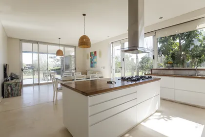 Cocina moderna con isla central de madera y amplios ventanales — proyecto Santa Barbara 121, por Build a Home Arquitectura, en B1648 Tigre