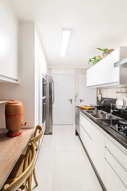 Cocina moderna blanca y madera con mesada longitudinal y equipos integrados — proyecto Apartamento Vila Leopoldina V, por Bordin E Soares Interiores