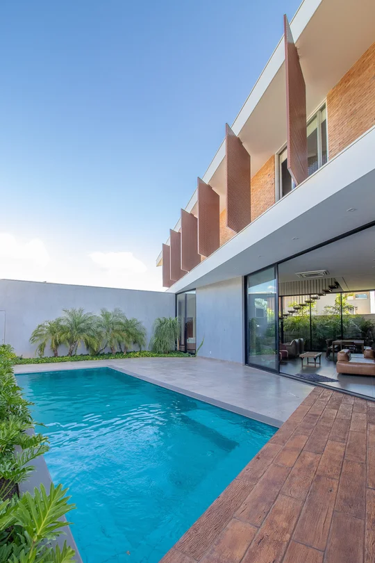 Piscina moderna con deck de madera y fachada de ladrillo contemporánea — proyecto Casa CaCle, por Studio Jordano Valota