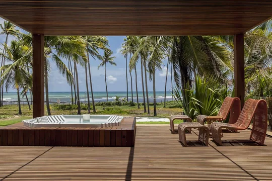 Terraza tropical con jacuzzi, reposeras y vistas al mar entre palmeras — proyecto Externas, por Xico Diniz