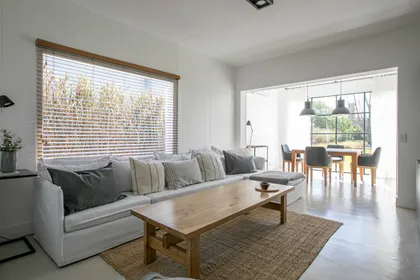 Sala de estar y comedor escandinava luminosa con sofá blanco y mesa de roble — proyecto Ampliacion Steel Santa Barbaba, por Arq. Lourdes Yarade Saravia, en Troncos del Talar
