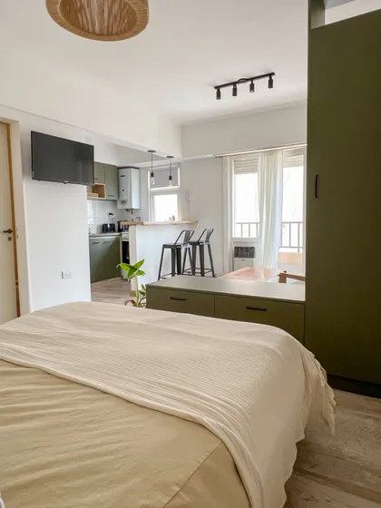 Ambiente moderno con cama amplia y cocina integrada — proyecto Reforma para alquiler temporal, por Gisela Salis, en Mar del Plata