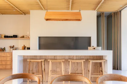 Cocina moderna con isla de madera y techo a la vista — proyecto El Refugio, por Grupo Pauta Arquitectura, en Pinamar
