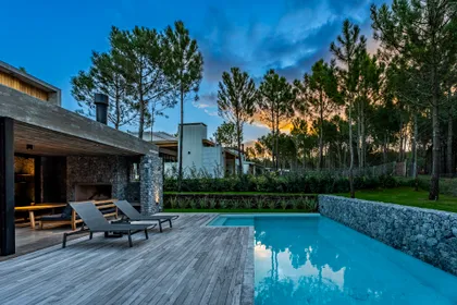 Piscina moderna con deck de madera y entorno de bosque — proyecto casa la huella, por Guerrero Arquitectos, en Pinamar