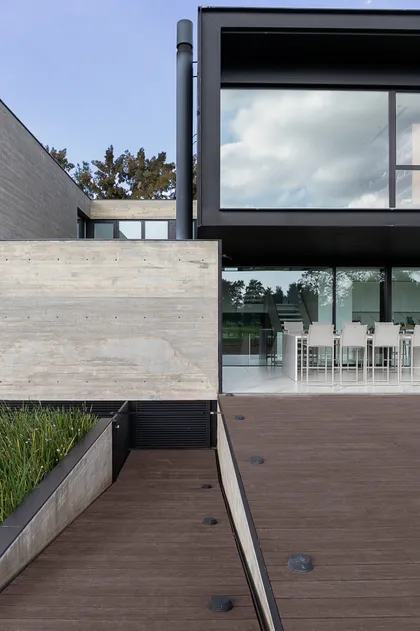 Fachada moderna con deck de madera y hormigón expuesto — proyecto PG.A, por Casa Cunia, en Buenos Aires