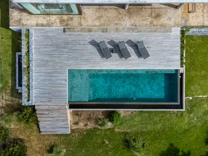 piscina infinita moderna con deck de madera y reposeras — proyecto CASA sobre el MAR, por Guerrero Arquitectos, en Pinamar