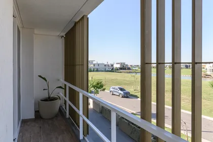 Balcón moderno con pantalla de lamas de madera y vista arbolada — proyecto CASA CALA, por Auge desarrollos & crowdfunding, en Nordelta